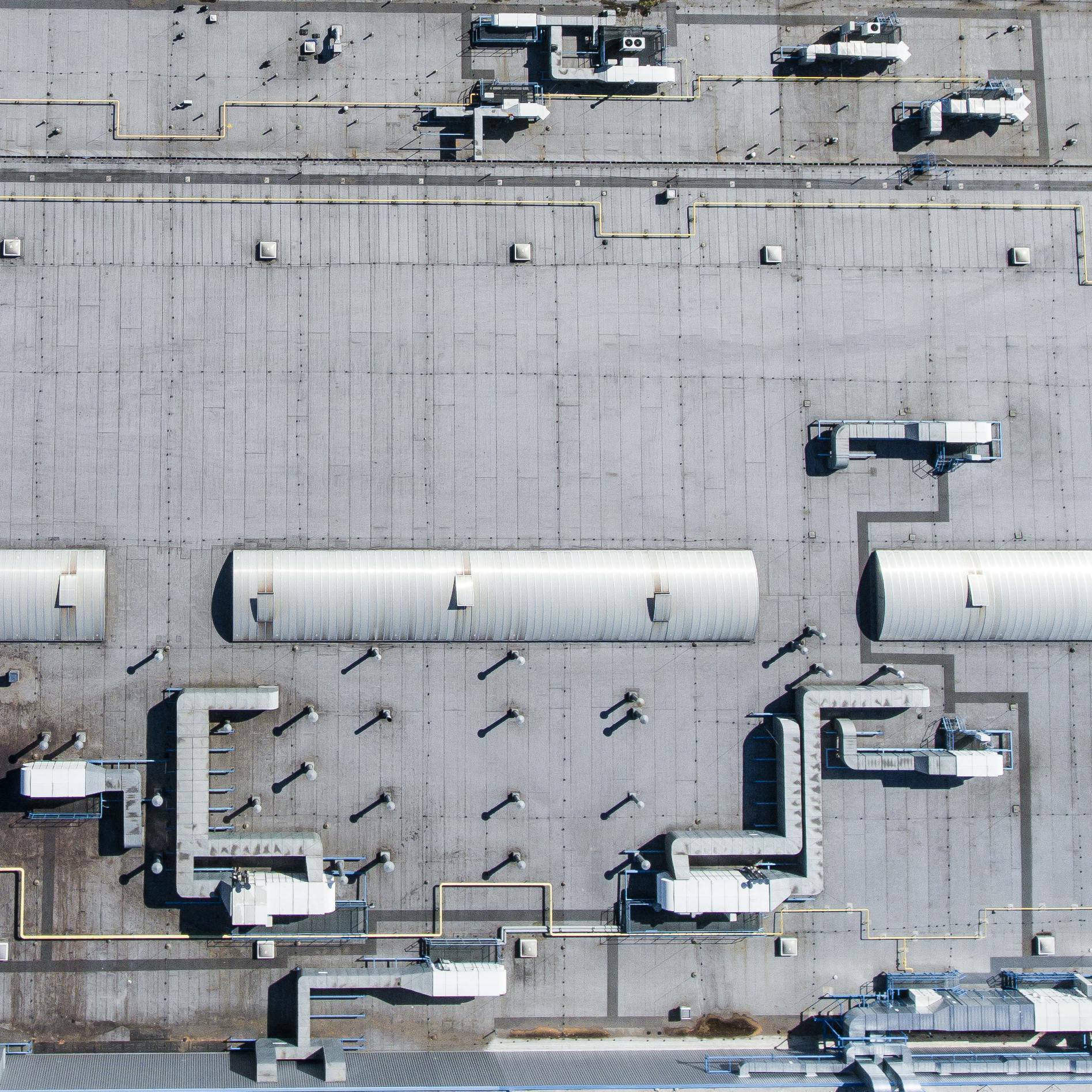 Aerial top view of a factory roof showcasing industrial pipes and structures.